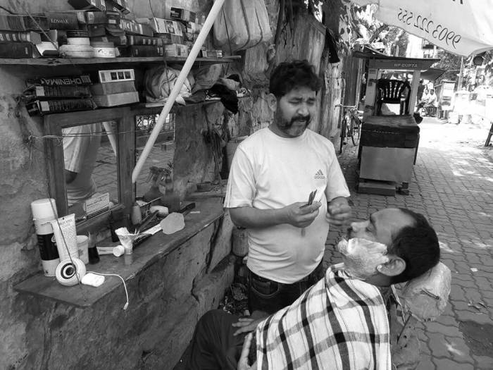 Street barber shaving his customer